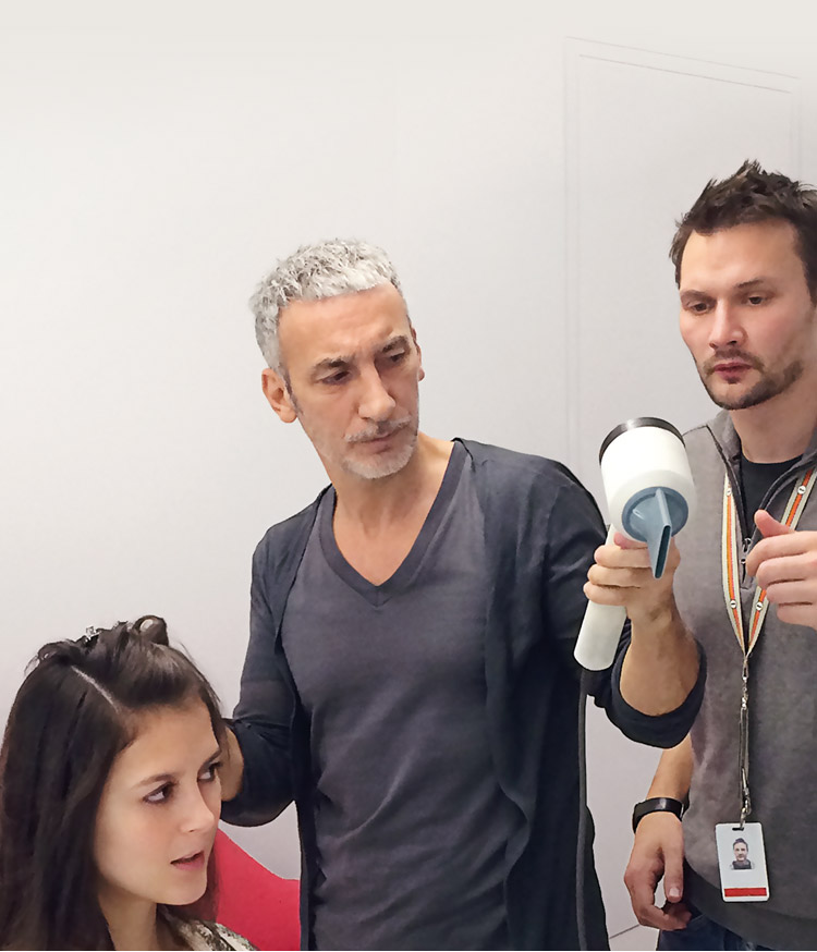 A hair stylist using the Dyson Supersonic™ hair dryer, accompanied by two Dyson engineers